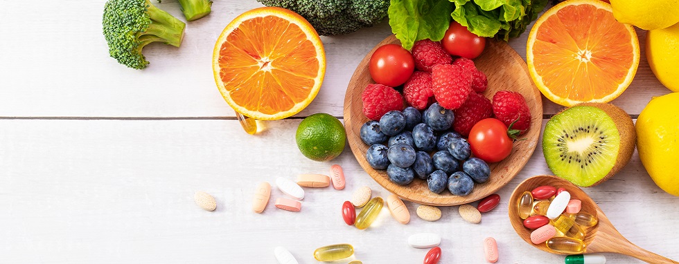 A top view of fresh fruits and vegetables with different medicine on a wooden spoon